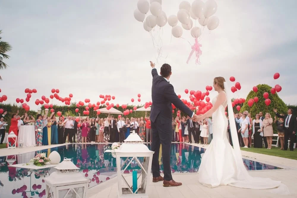 Invitados y novios soltando globos blancos en una boda en Tarragona, fotografía de eventos al aire libre.